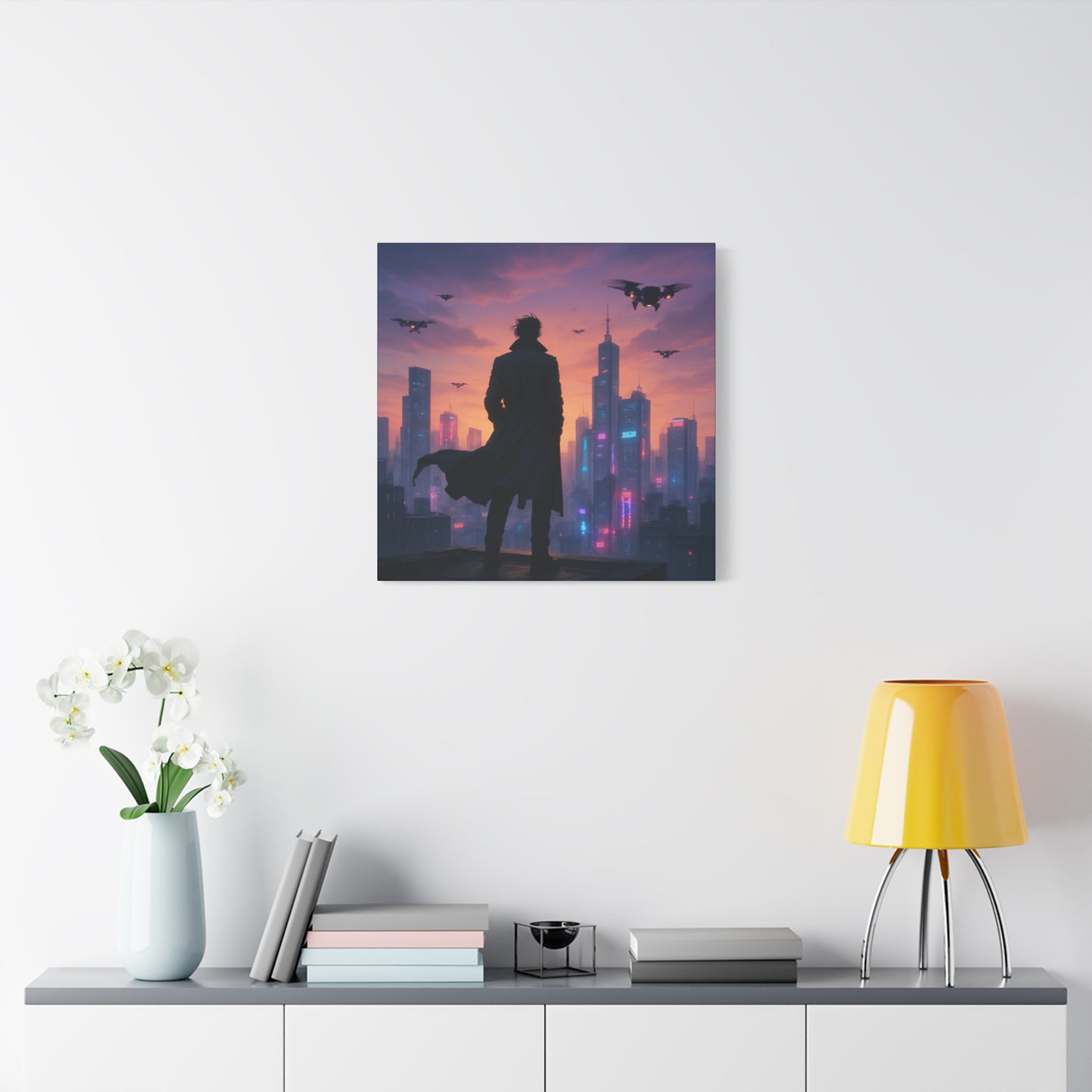 Framed artwork of a silhouette against a cityscape with a purple and pink sky, displayed on a wall above a shelf.