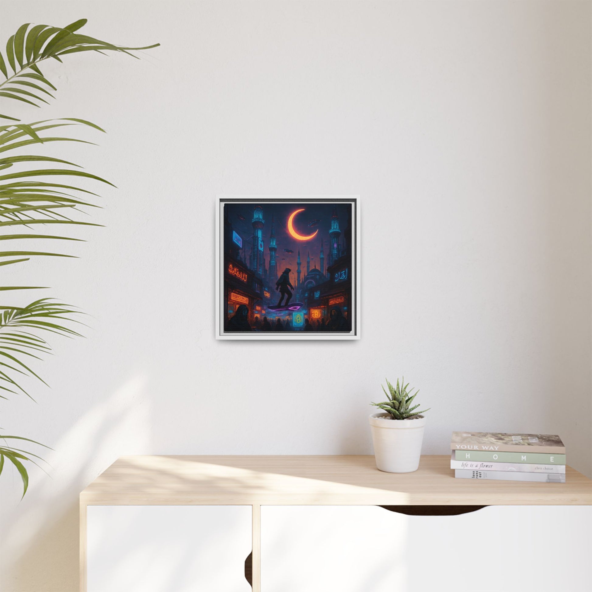 Framed artwork of a cityscape with a crescent moon on a white wall above a wooden desk.